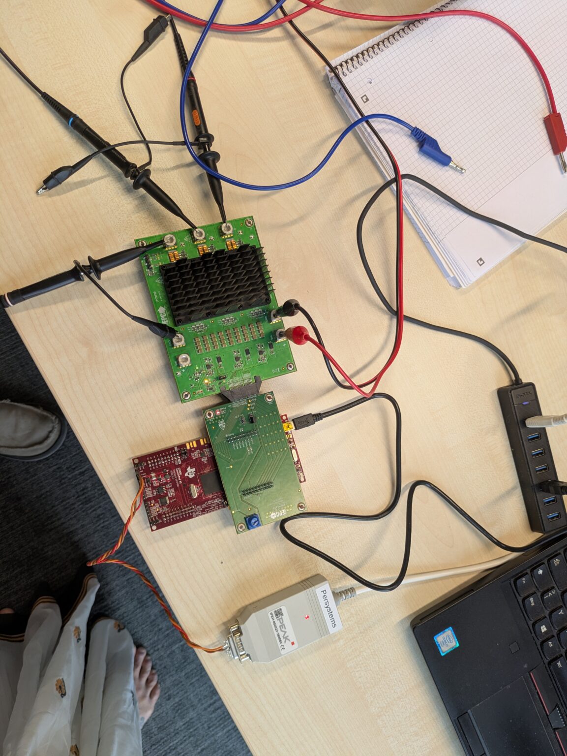Inverter-Platine am Prüfplatz mit Oszilloskop-Tastköpfen, Entwicklungsboard und Notizen