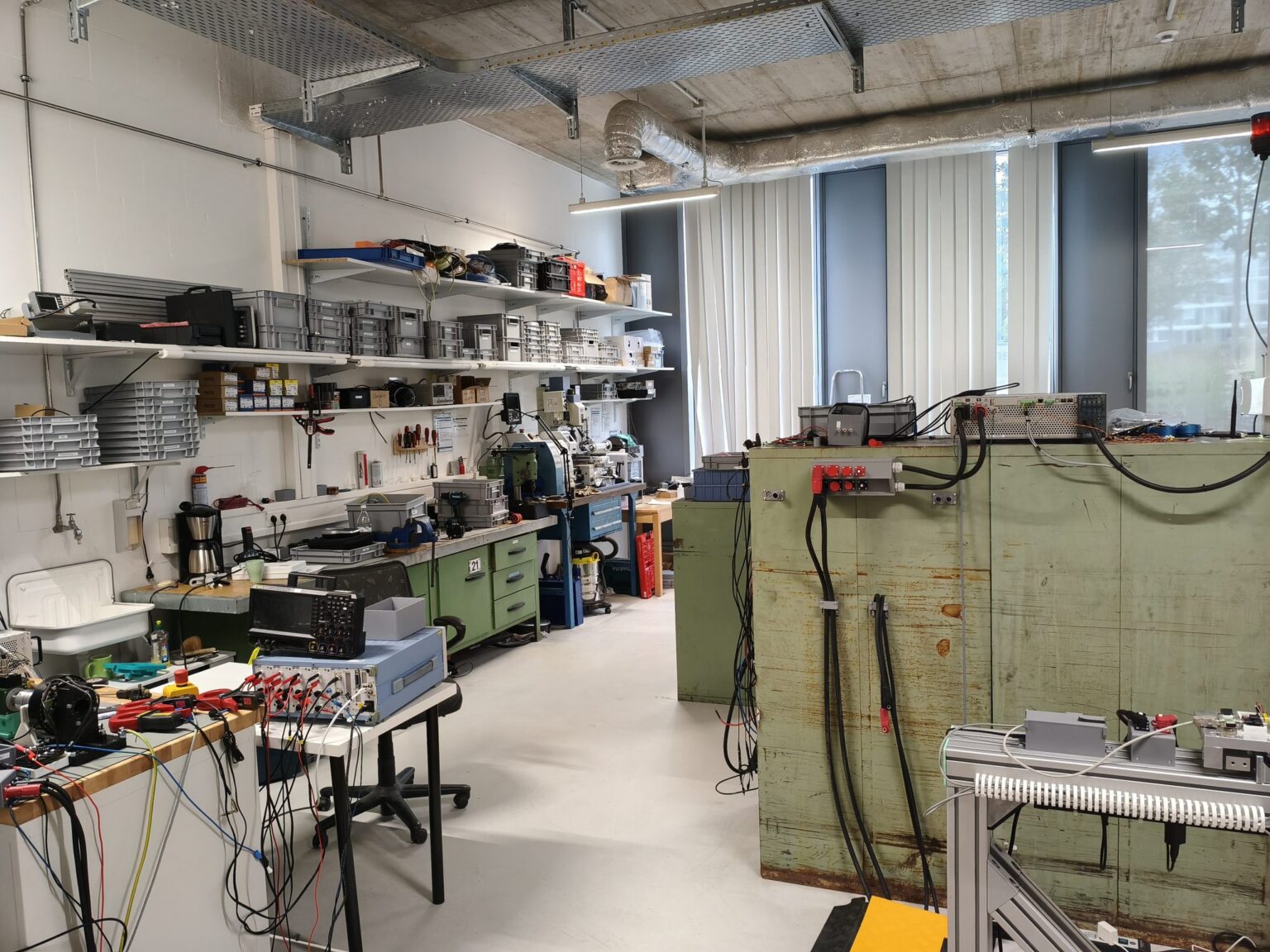 Werkstatt von Persystems in der TechBase Regensburg: Werkbänke, Regale mit Material, Prüfaufbauten